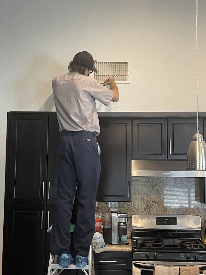 Technician inspecting an air vent during HVAC service in Yazoo City